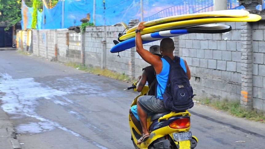 Two Balinese make their way to Kuta beach with surfboards stacked high, July 5, 2011. (Damien Morris)