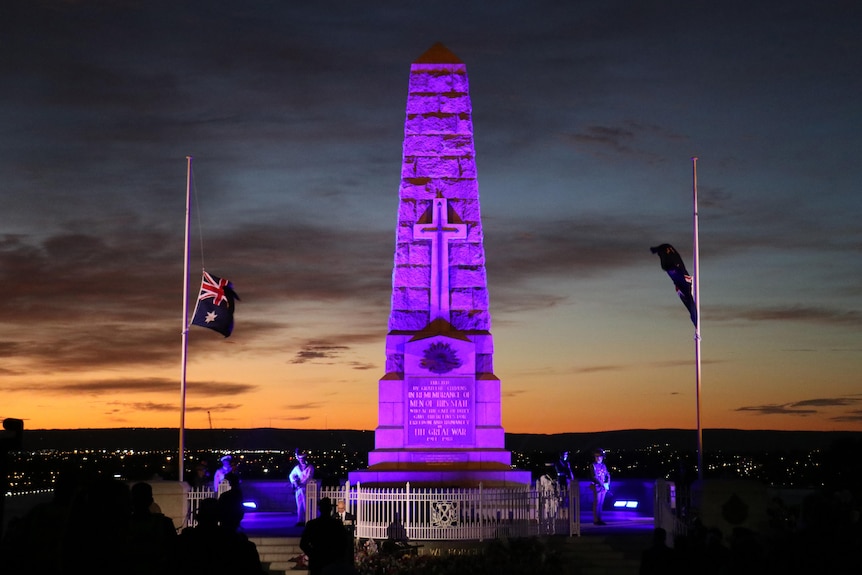 Kings Park war memorial at dawn, lit in purple with fluttering Australian flags on either side
