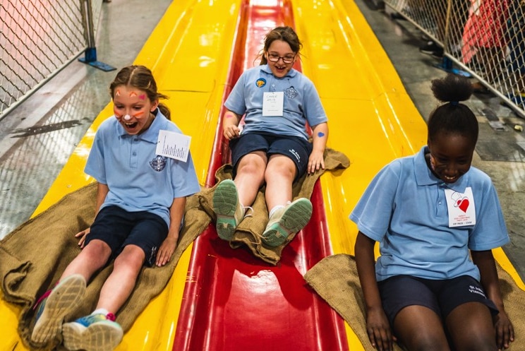 Three girls go down a slide.