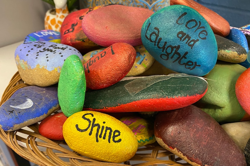Colourful painted stones with words on them in a basket