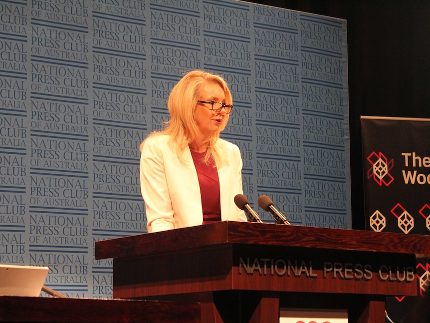 Bridget McKenzie stands on stage in front of National Press Club banner, speaking into microphone