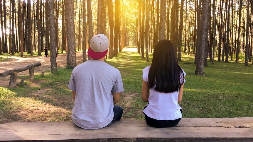 Couple sitting apart in a park, in a story about why some Christians still abstain from sex before marraige.