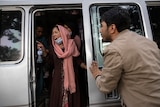 A woman in a pink headscarf yells from white van