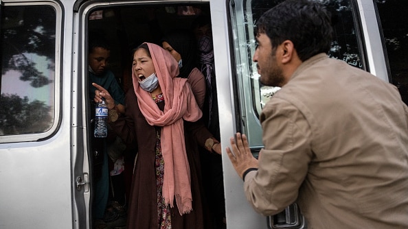 A woman in a pink headscarf yells from white van