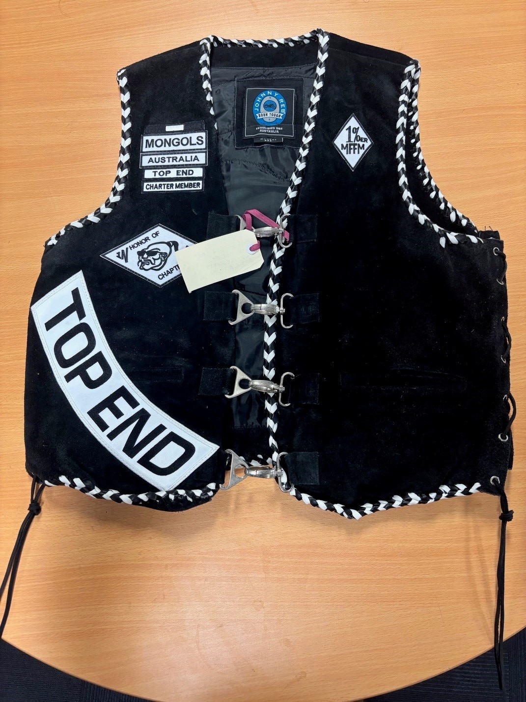 A black motorcycle vest sits on a wooden table.