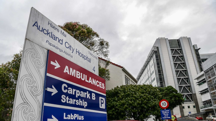 A sign outside a hospital and buildings in the background