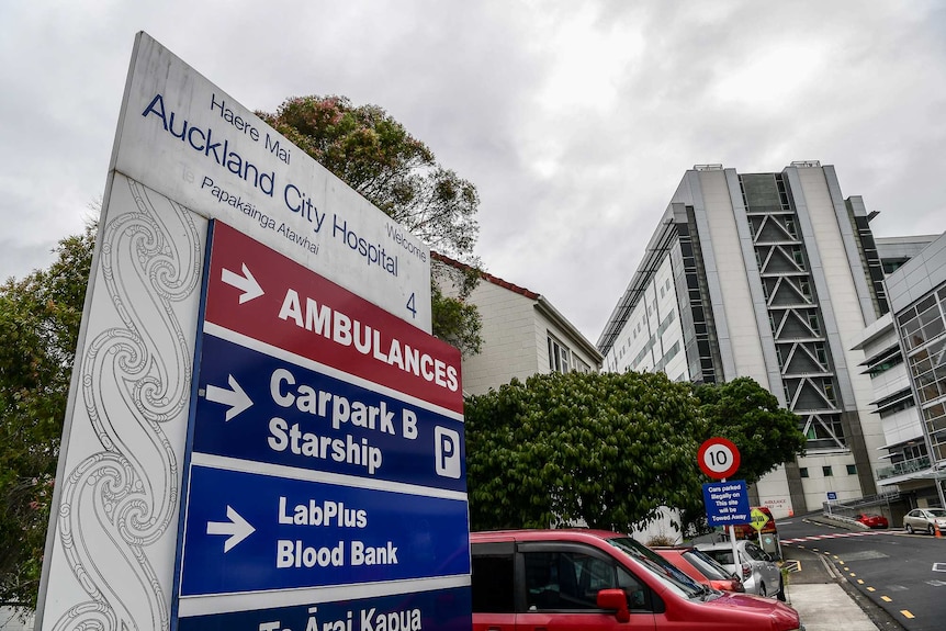 A sign outside a hospital and buildings in the background