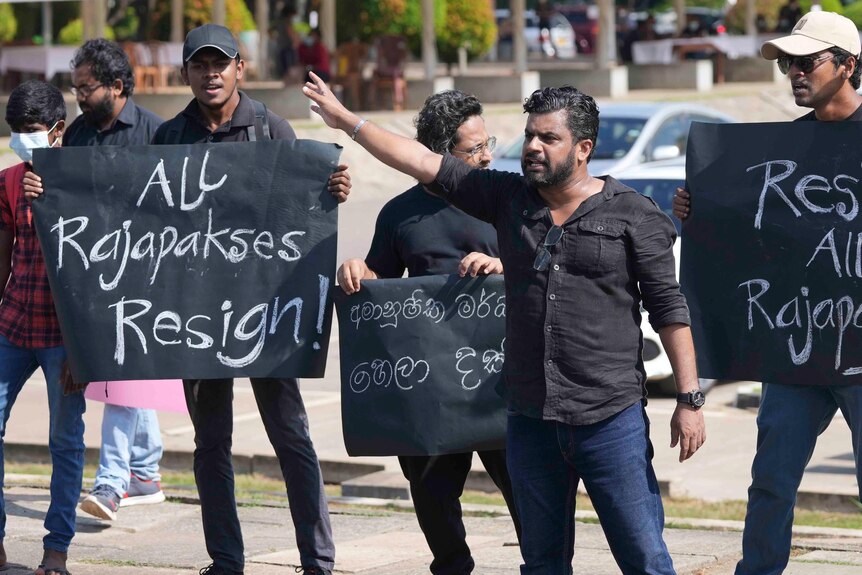 Protesters hold signs reading "all Rajapaksas resign" 