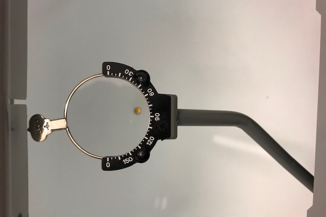An eye test with measuring equipment around a glass circle.