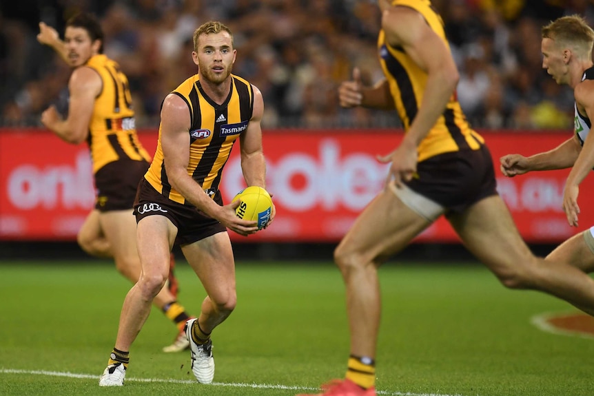 Hawthorn's Tom Mitchell handballs against Collingwood