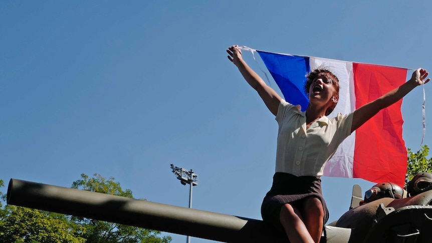 A woman waves a French flag during celebrations of the liberation from Nazi occupation 75 years ago.