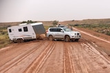 A four-wheel drive and a caravan bogged on a muddy dirt road in outback South Australia.