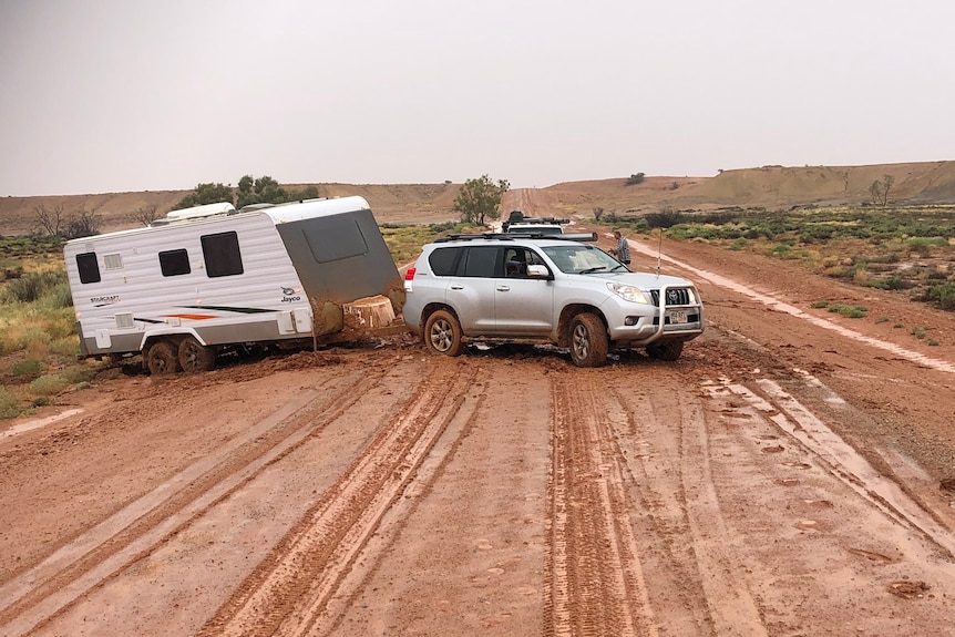 A four-wheel drive and a caravan bogged on a muddy dirt road in outback South Australia.