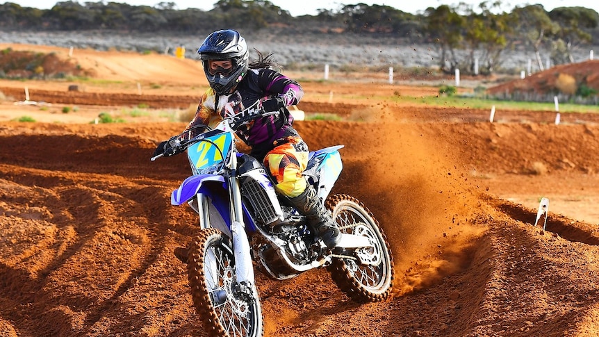 Christina Vithoulkas riding a motorbike on a dirt track.