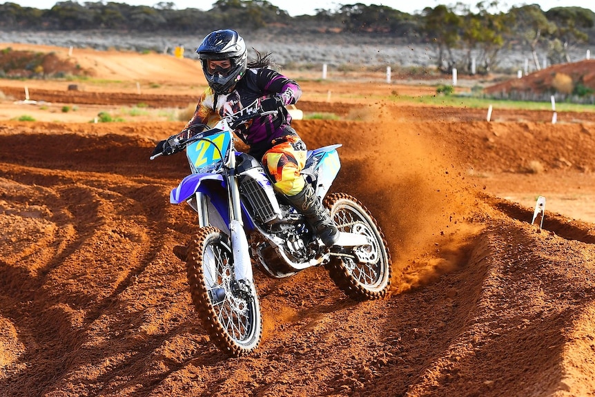 Christina Vithoulkas riding a motorbike on a dirt track.