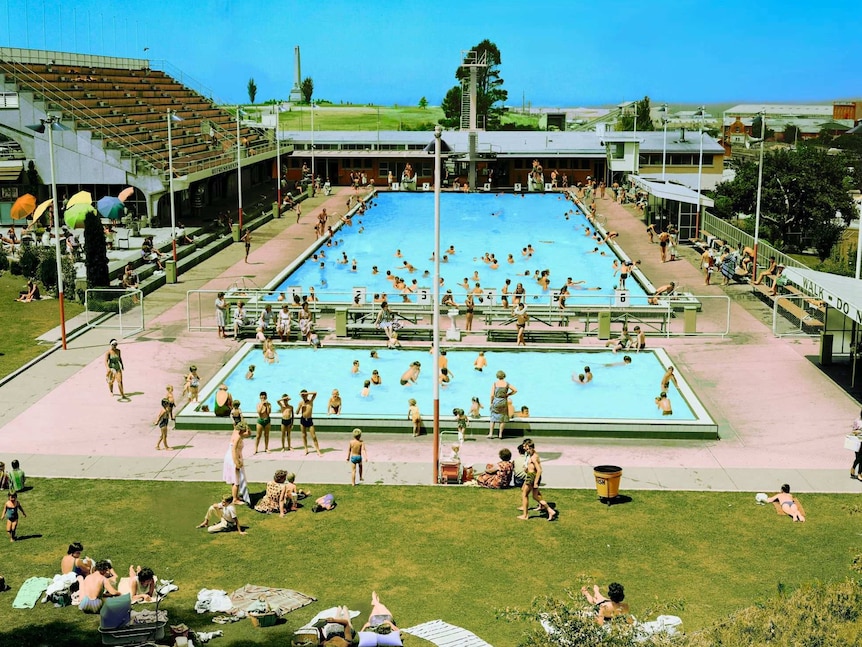 Lots of people in an outdoor olympic swimming pool