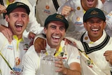 Australia's men's cricket team pose with a crystal urn-shaped and shout in front of a sign reading "THE ASHES".
