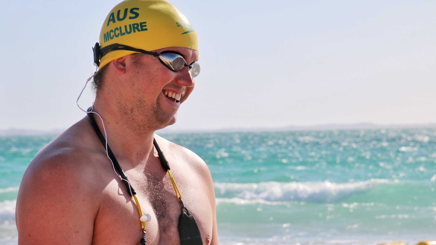 Blind swimmer Jeremy McClure in side profile on the beach in swimming gear.