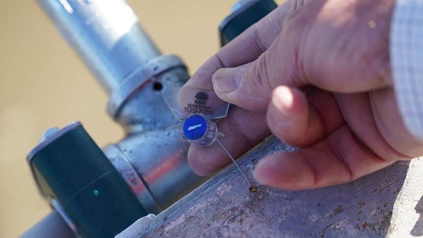 A close up of a tamper-proof seal on a water pump with NSW Government identification.