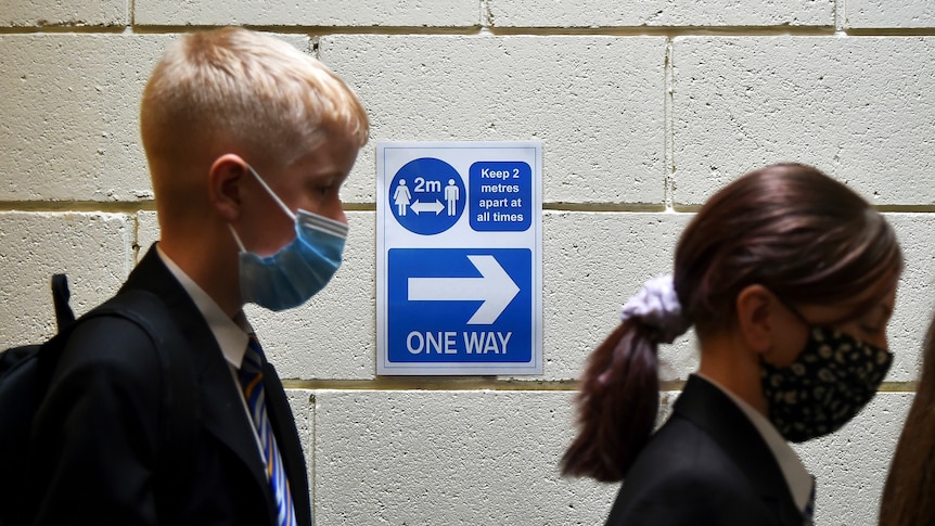 Two school students queue for COVID testing while wearing face masks