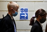 Two school students queue for COVID testing while wearing face masks
