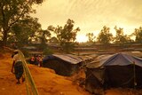 A man carries bamboo past newly constructed huts in a Rohingya refugee camp in southern Bangladesh.