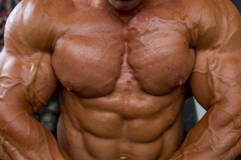 The torso of a male body builder with dark tan on his skin.