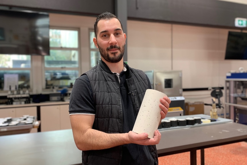 Yanni Bouras, an engineering professor at Victoria University, with a tube of a concrete-like substance.