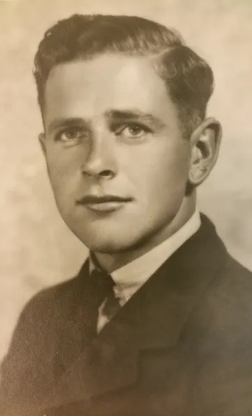 A sepia toned portrait of a man with brown hair wearing a suit.