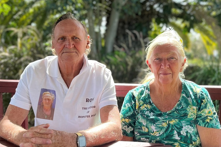 an older man and woman sitting at an outdoor table