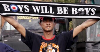 A Persija fan holds a banner reading: "Boys will be boys".