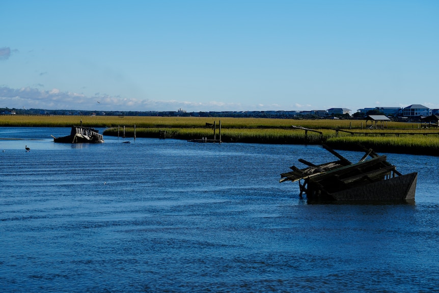 A boat house is overturned and broken pieces of a dock lie in the inlet.