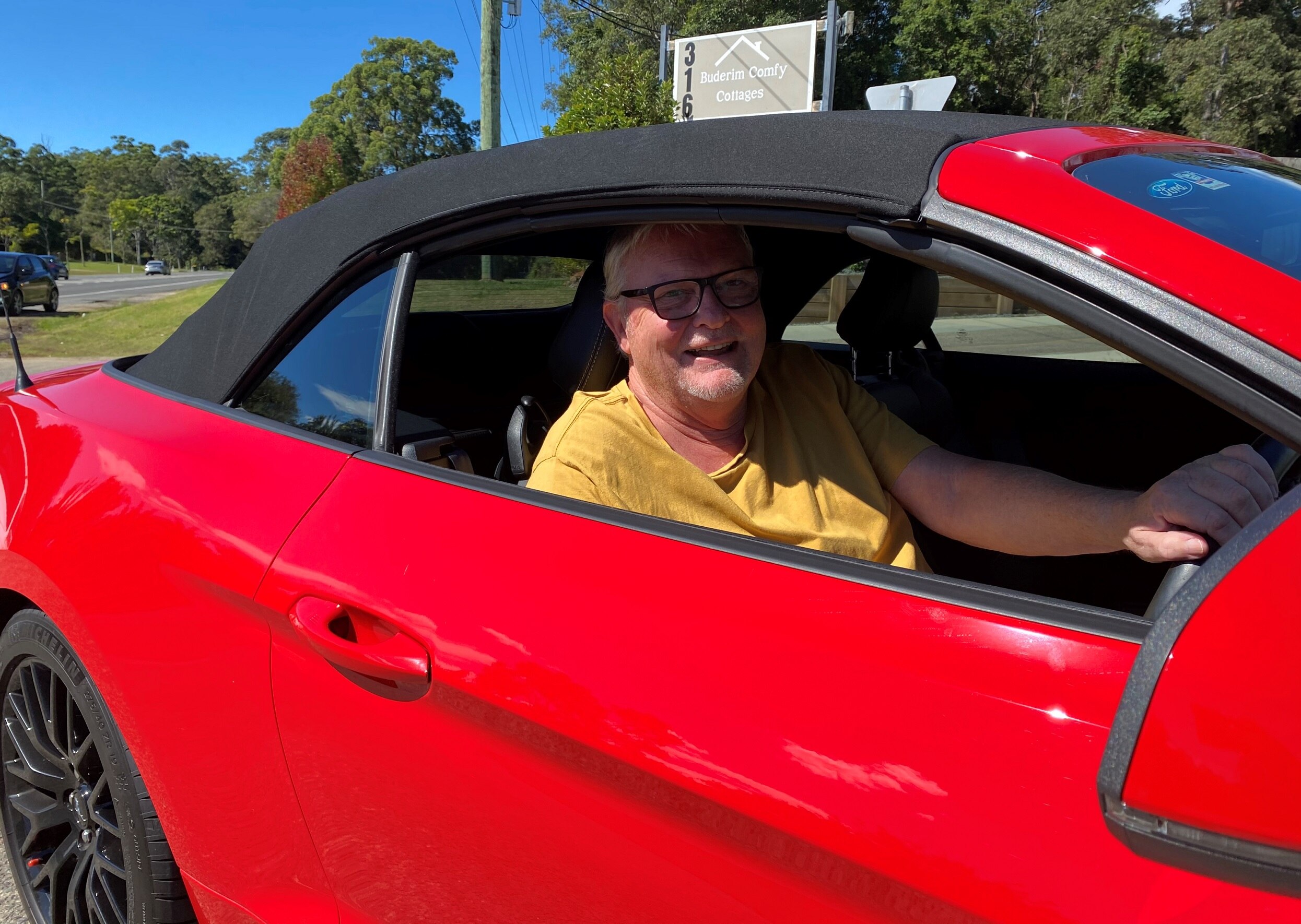 A smiling driver behind the wheel on the driveway of a petrol station