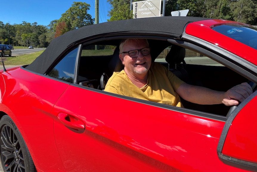 A smiling driver behind the wheel on the driveway of a petrol station