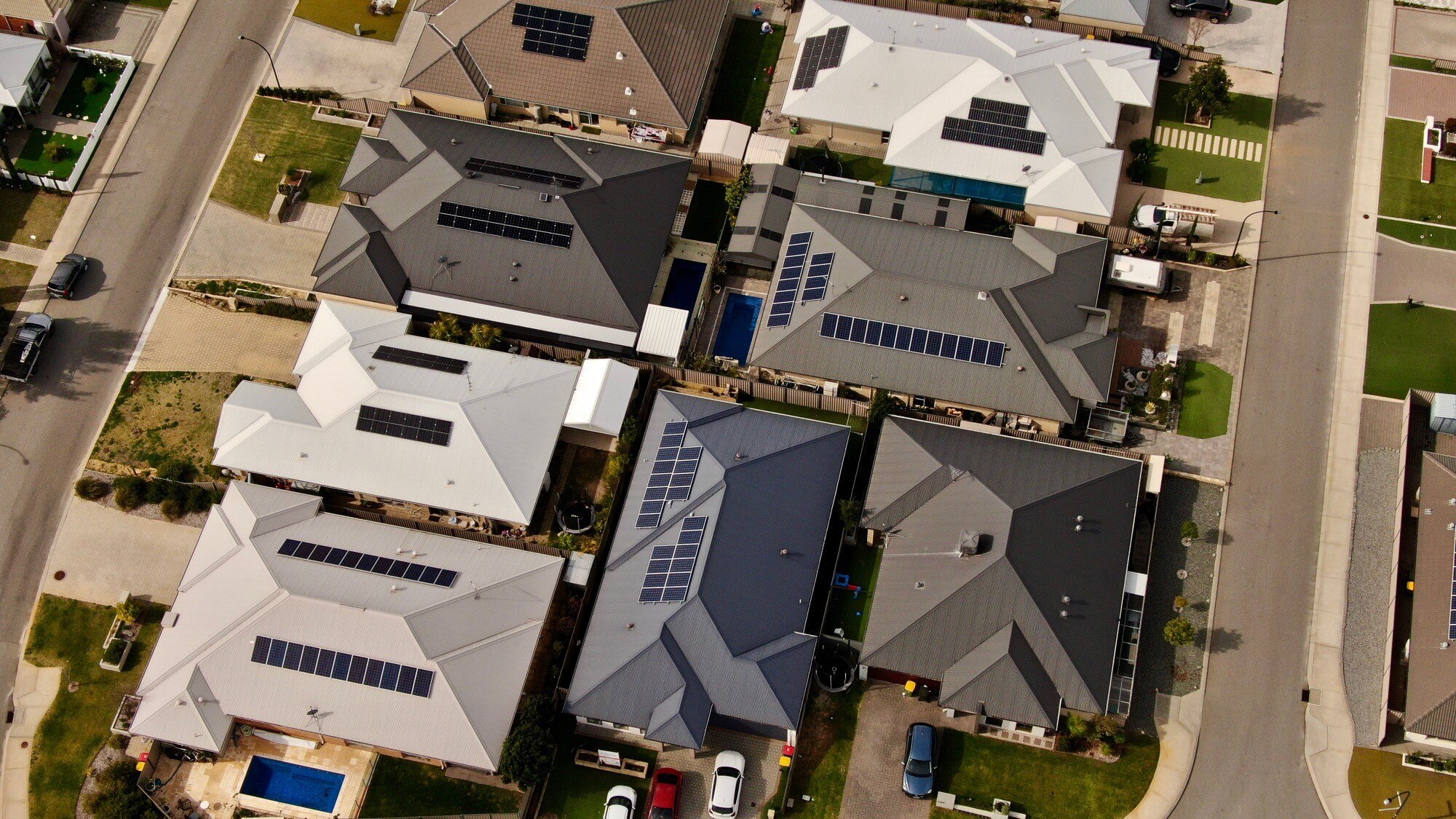 Aerial shot of a group of houses, all of which have solar panels on their roof