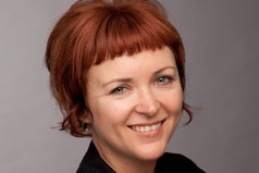 A woman with short red hair smiling.