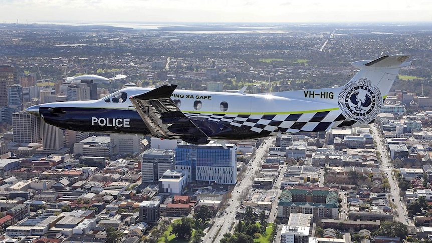 A police aircraft flies over Adelaide.