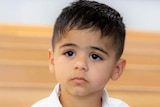 A boy with white shirt looking at camera