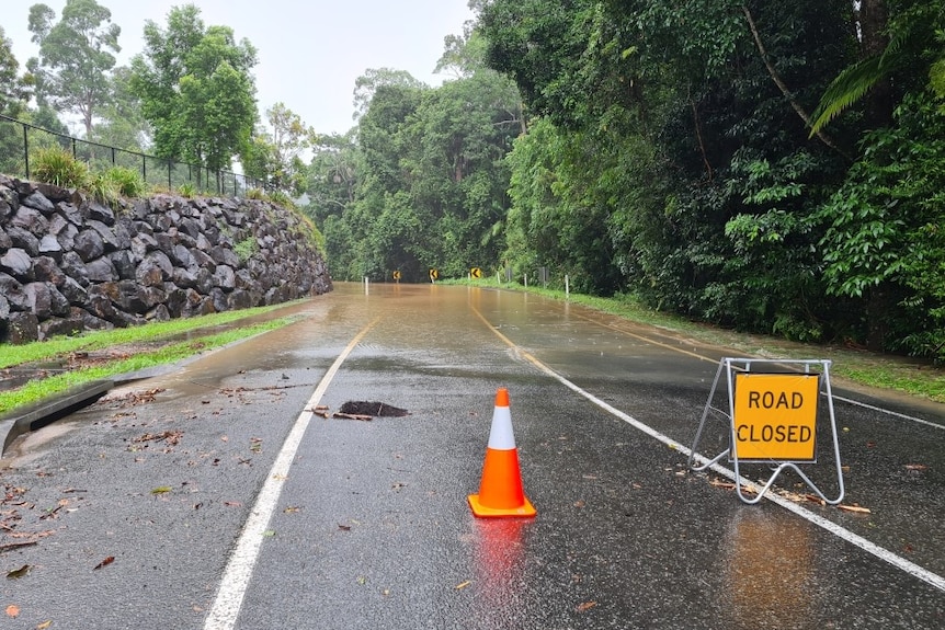 Signs are erected on a street at Buderim to stop cars from travelling on it due to water over the road.