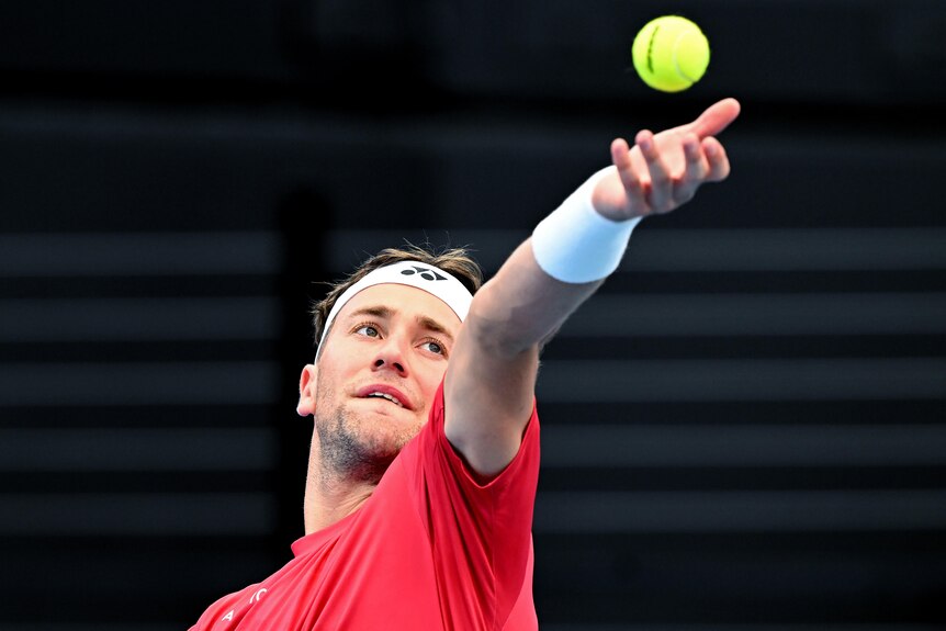 Casper Ruud throws a tennis ball up in the air