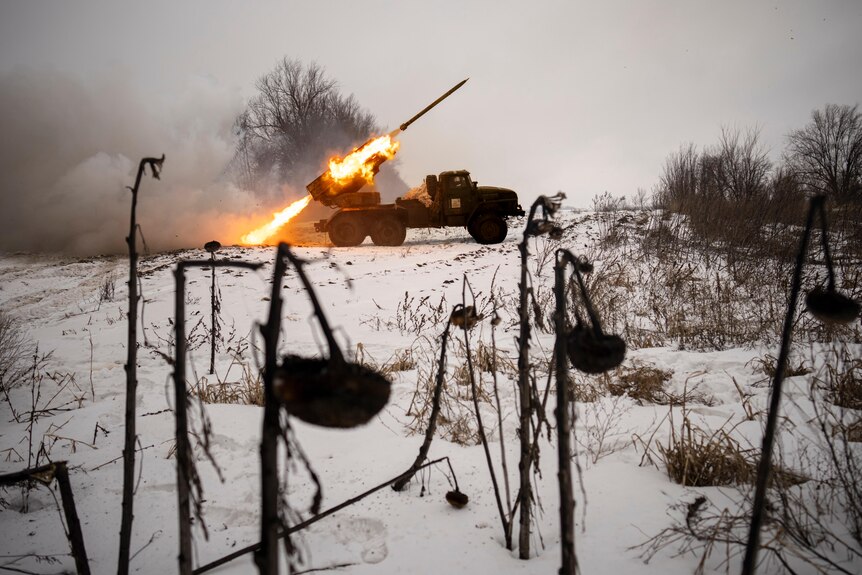 A truck mounted rocket launcher fires a rocket while parked on snowy ground.