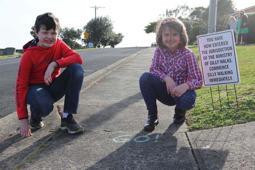 Two children next to a silly walking sign.