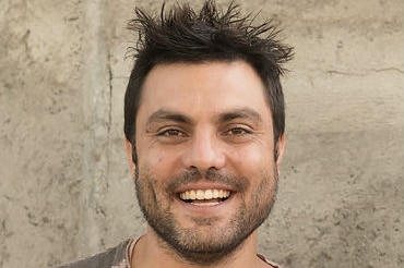 A man in a beige tshirt smiling