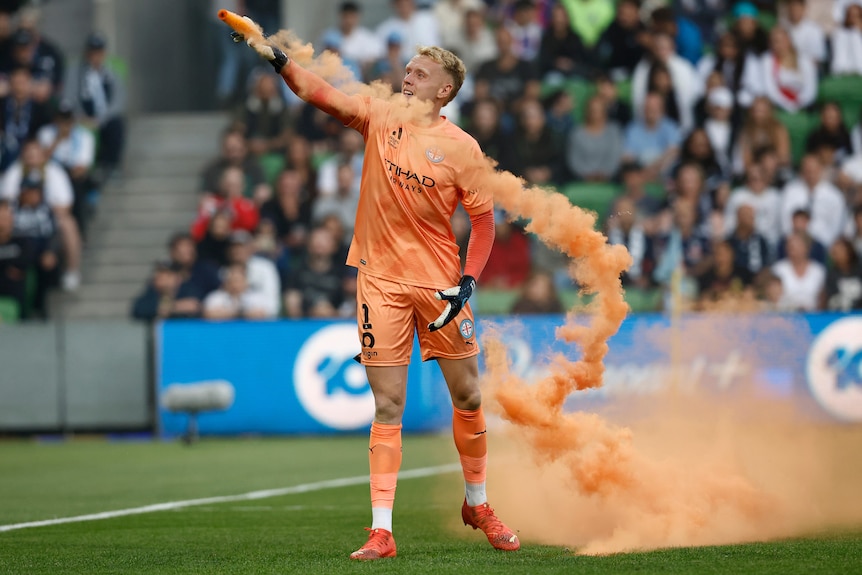 Tom Glove of Melbourne City picks up a flare to remove it from the pitch during an A-League Men match.