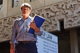 A man holds a folder while standing outside the Townsville law courts
