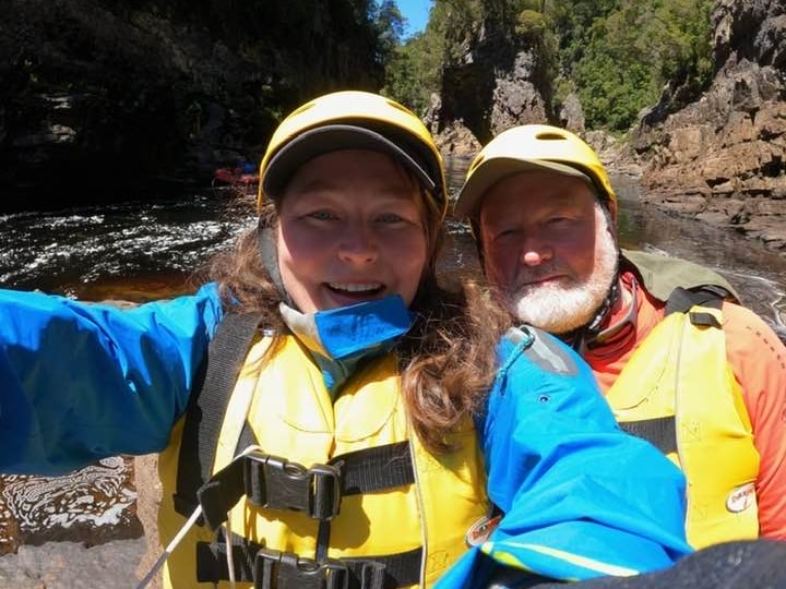 Selfie of two people with life jackets on in front of river 