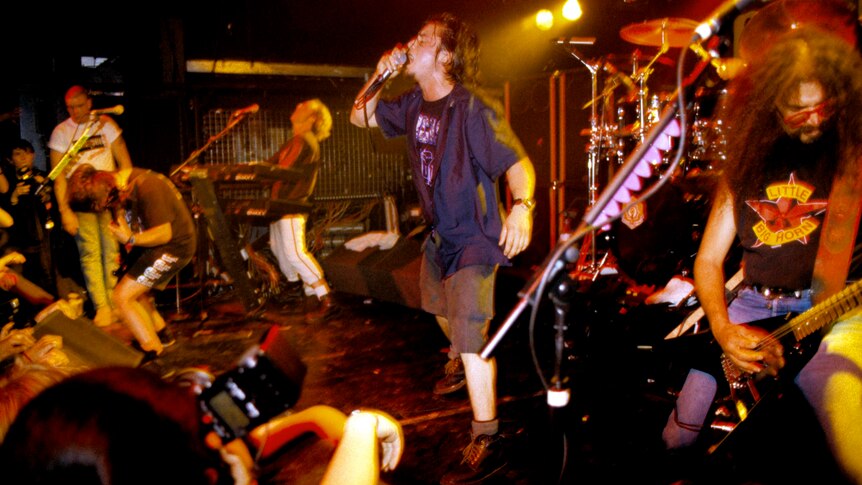Five members of rock band Faith No More performing on stage