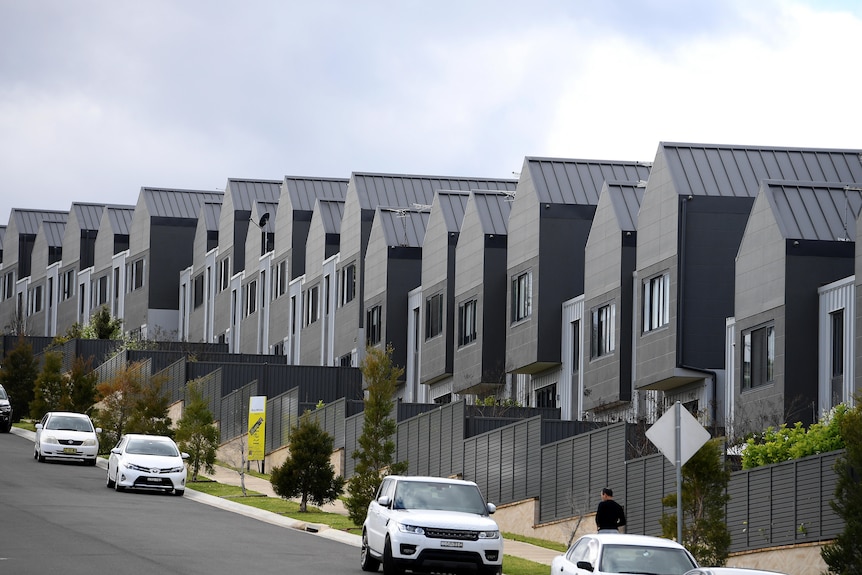 a row of houses with cars parked our the front