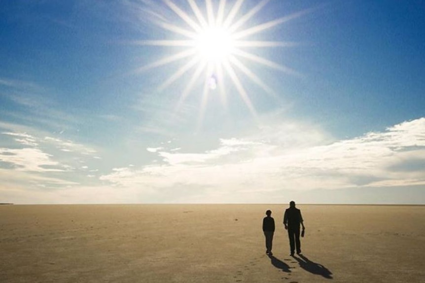 Two people walk across a dry salt lake