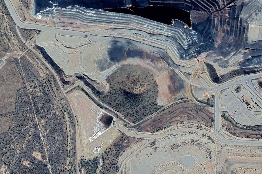 A Google Earth images shows a green hill surrounded by mining operations.